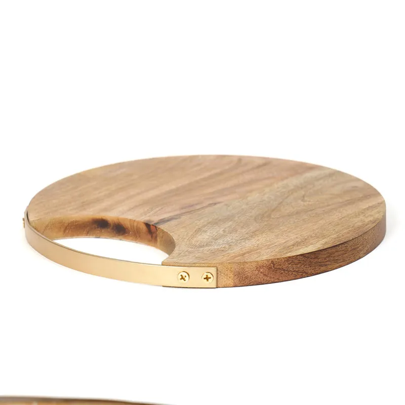 Side view of a round mango wood chopping board with a brass edge