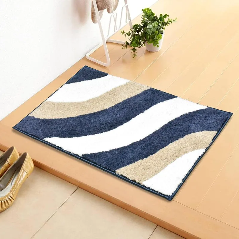 Blue, white and beige bath mat with wavy pattern placed near a doorway