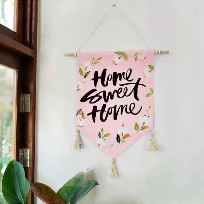 Pink Home Sweet Home wall hanging displayed on a white wall near a window