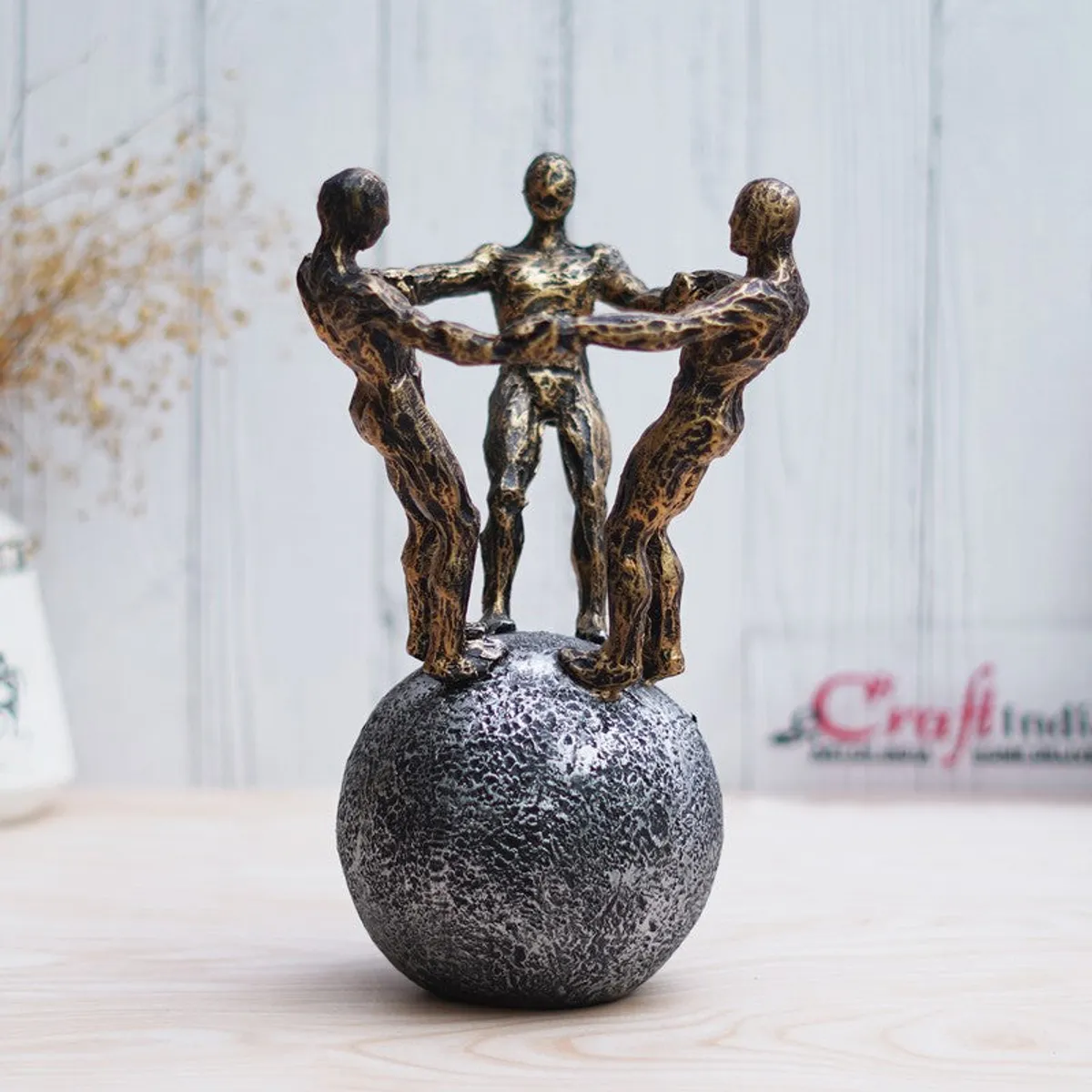 Three-figure unity sculpture in gold on a textured grey sphere