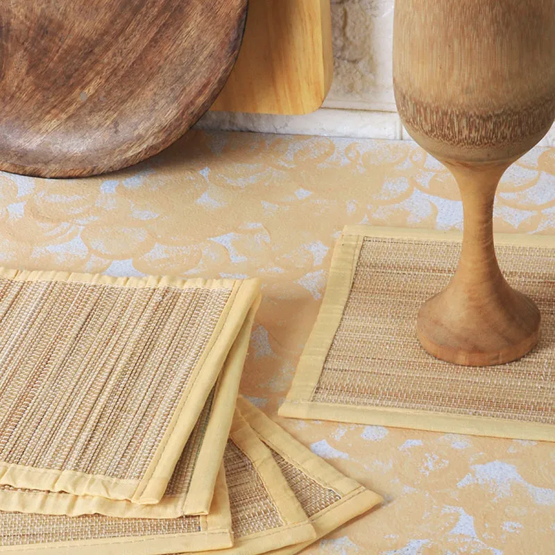 Close-up of beige square coasters with a wooden goblet on one coaster