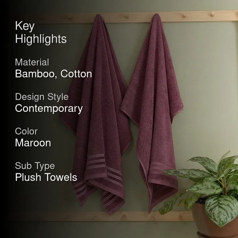 Maroon bath towels hanging in a bathroom with a green plant