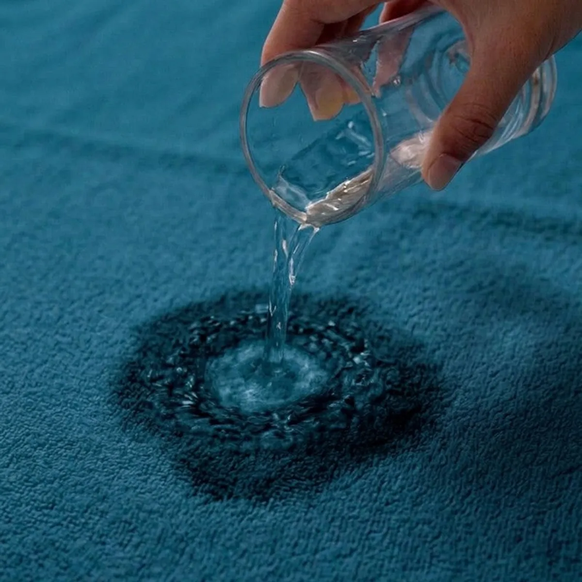 Water being poured onto the absorbent surface of a blue bath towel