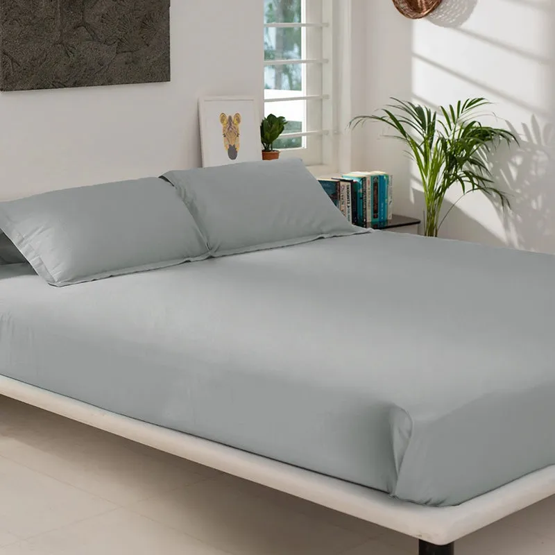 Light grey fitted bedsheet styled on a low bed with matching pillow covers