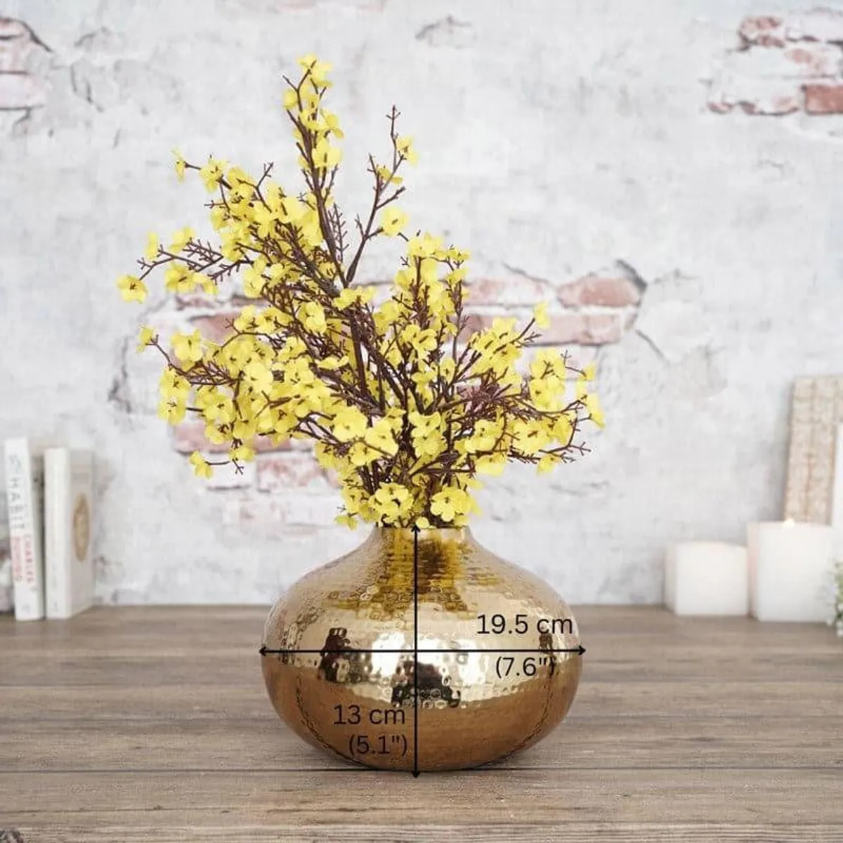 Gold hammered urn vase holding yellow flowers on a tabletop