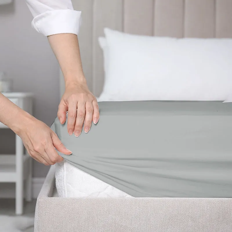 Close-up of a light grey fitted bedsheet stretched over a mattress corner