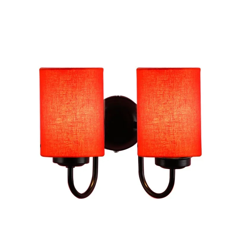 Lit orange double-shade wall lamp with black curved arms