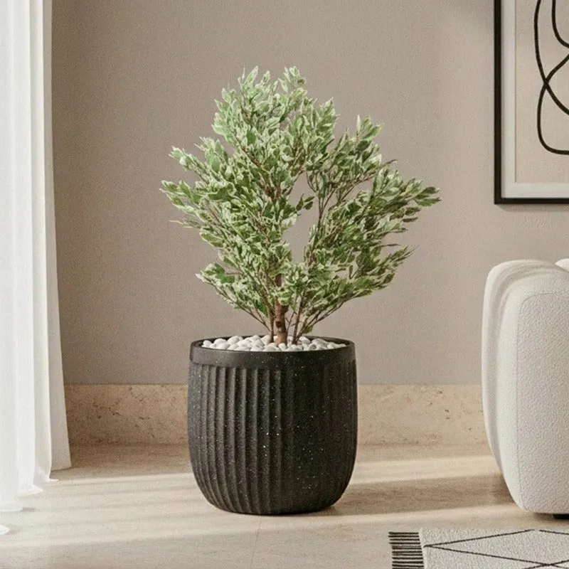 Black ribbed planter with a leafy plant beside a contemporary sofa