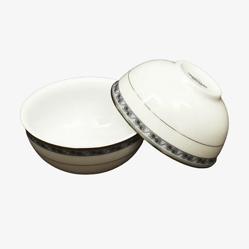 Two white porcelain bowls with ornate dark floral and gold borders.