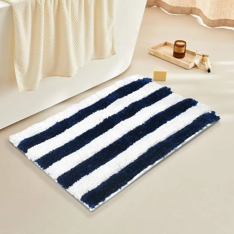 Blue and white striped rectangular bath mat beside a bathtub