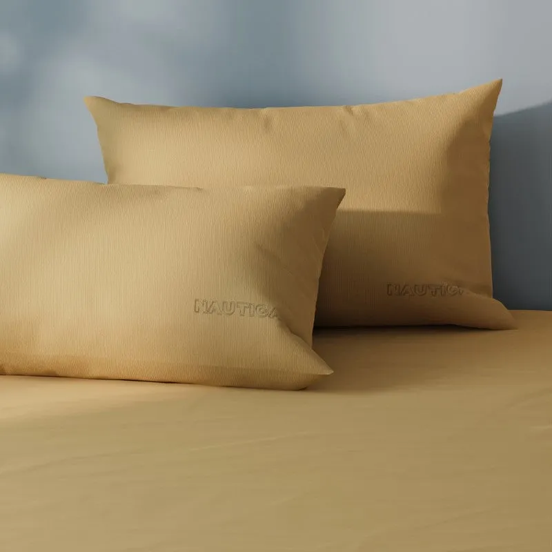 Close-up of matching mustard-yellow satin cotton pillow covers and bedsheet