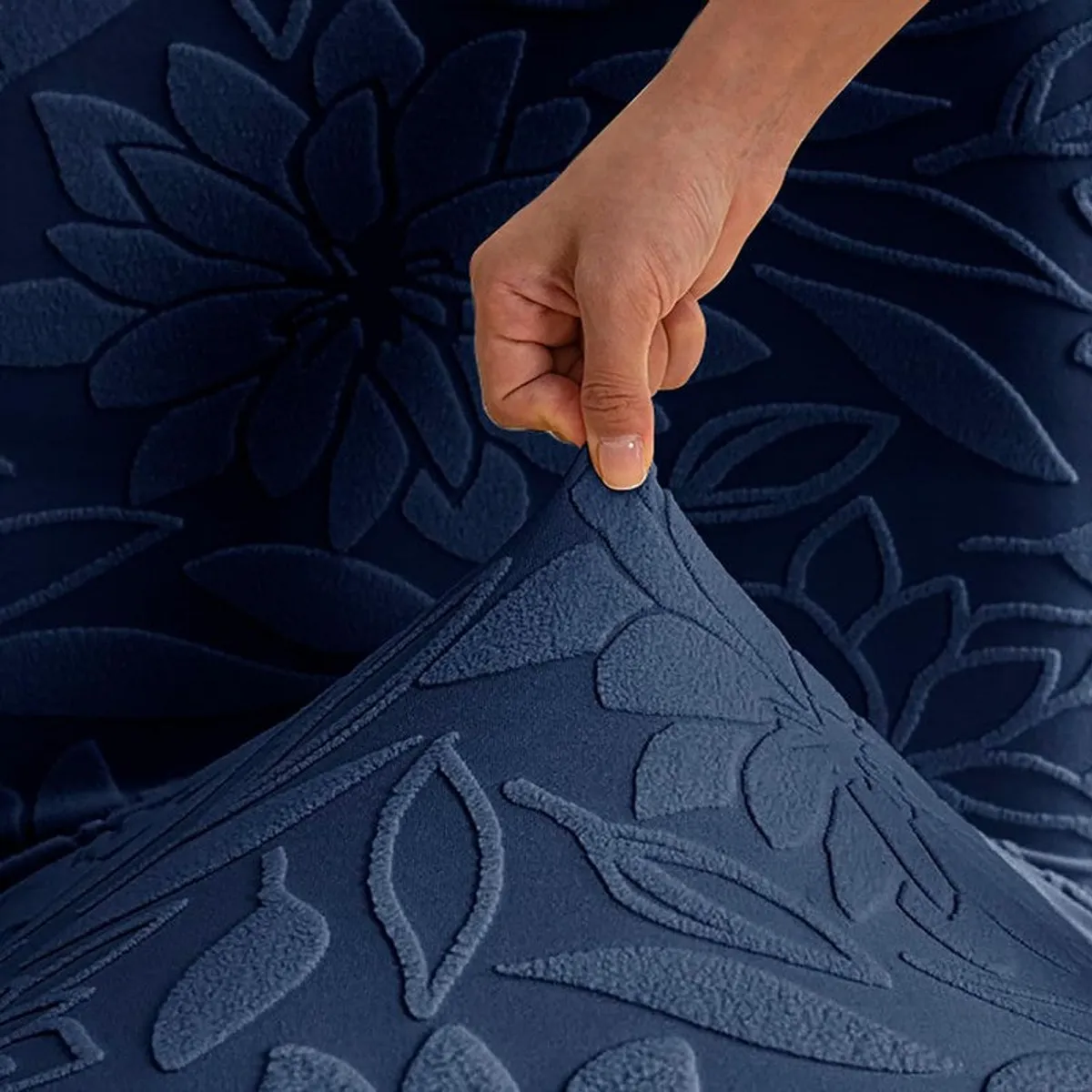 Close-up of stretchy blue floral chair cover fabric being pulled