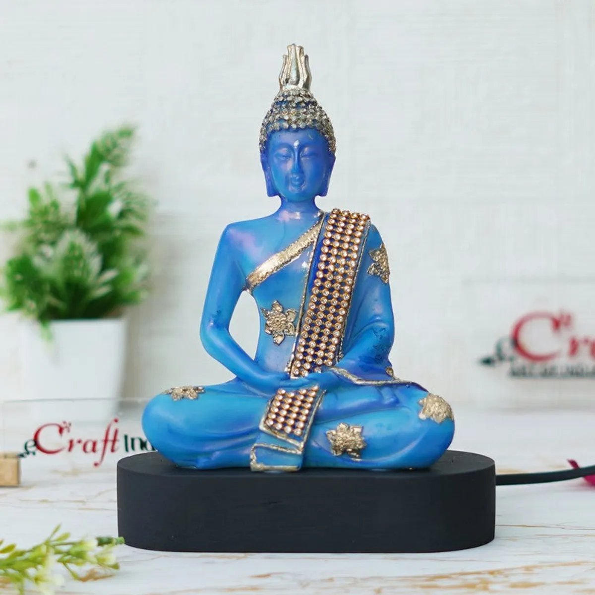 Blue Buddha idol with gold detailing on a black base