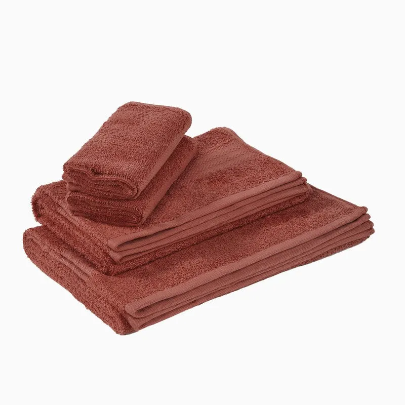 Stacked rust bath and hand towels on a white background