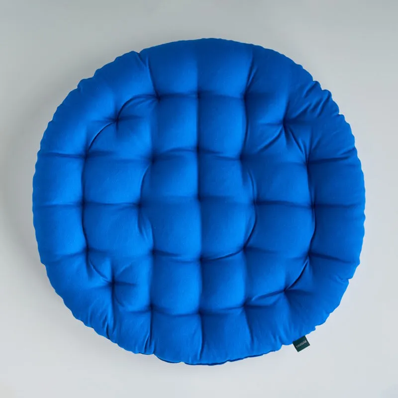 Top view of a round blue cushion with a softly textured surface.