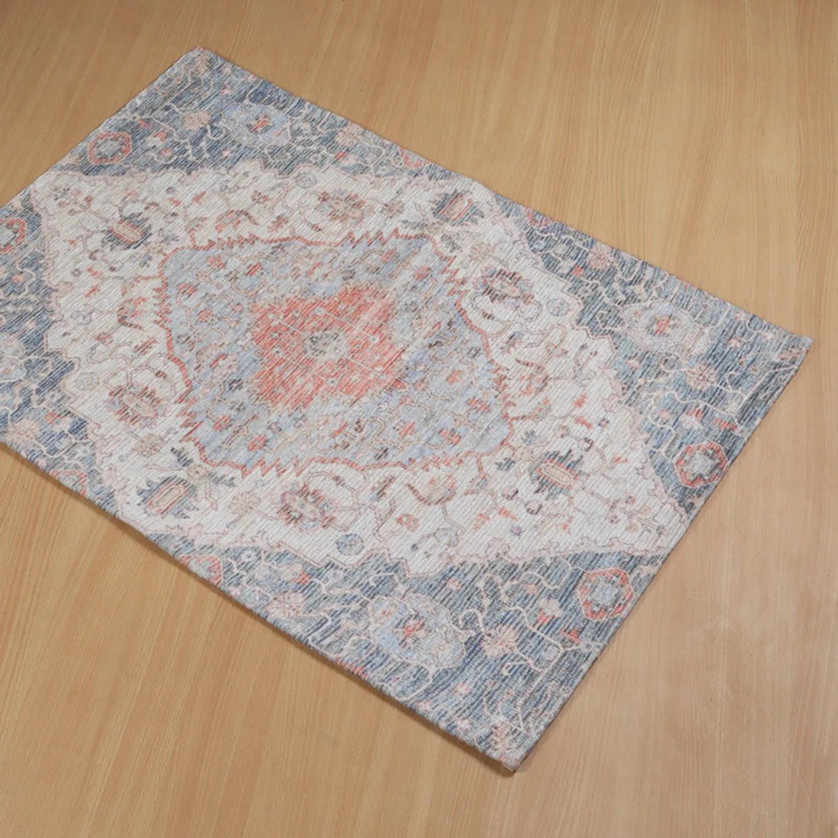 Top view of a rectangular ethnic patterned doormat with beige, blue and coral tones