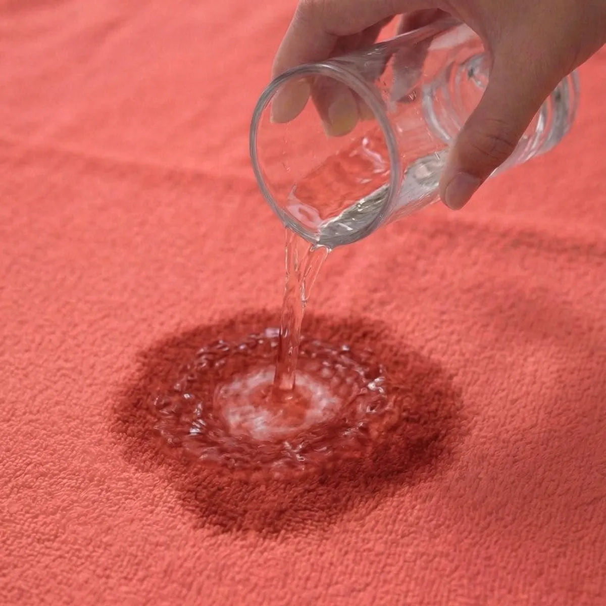 Water being poured onto a peach towel surface