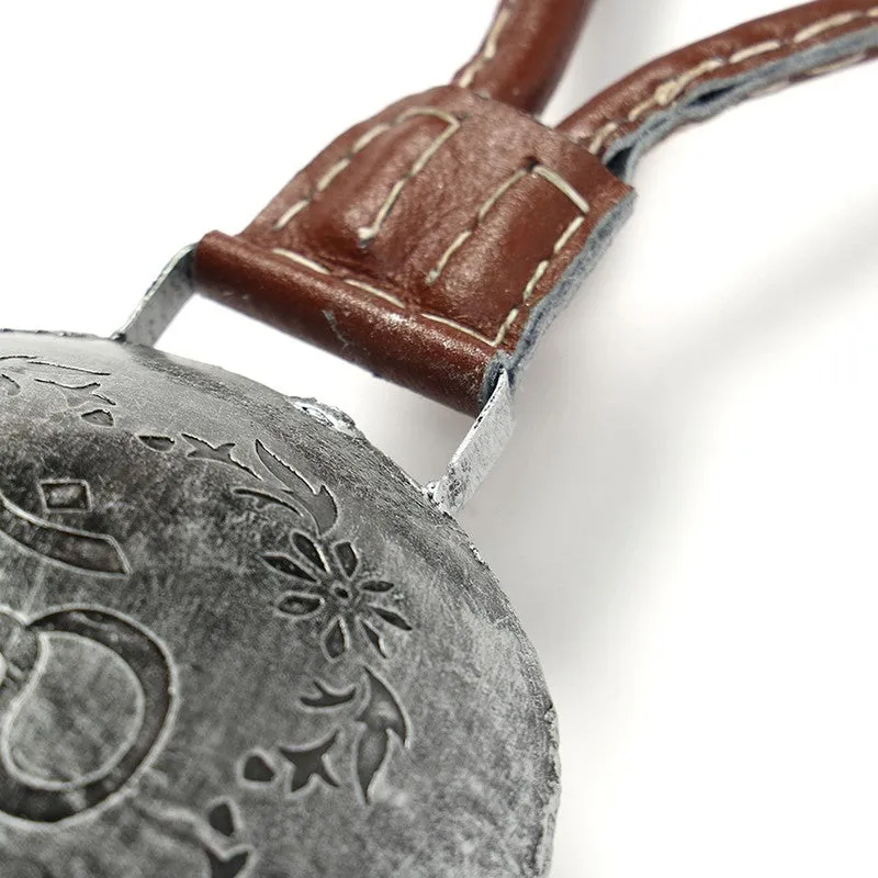 Close-up of the bell's silver floral detailing and brown hanging loop