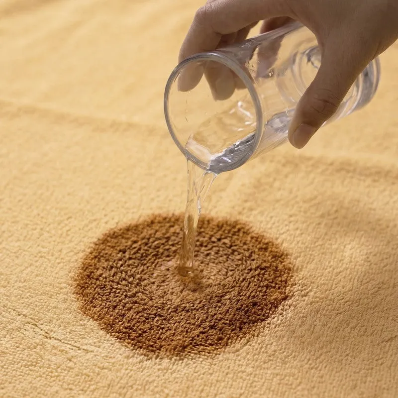 Water being poured onto the absorbent surface of a yellow bath towel