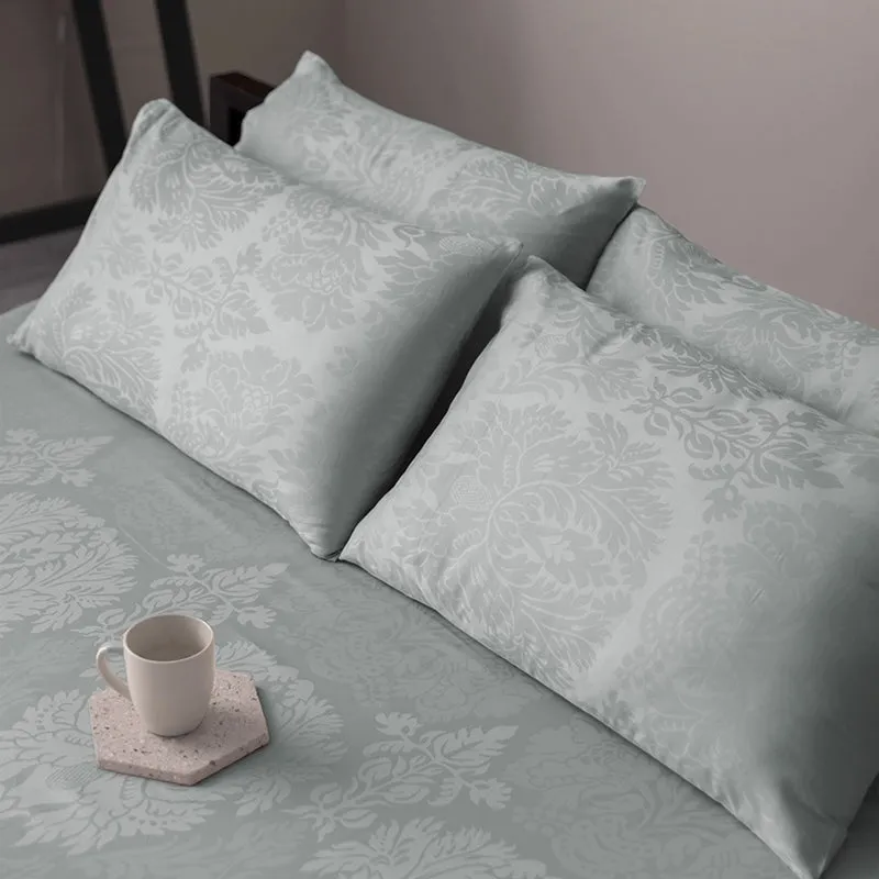 Light grey floral bedding with matching pillows and a cup