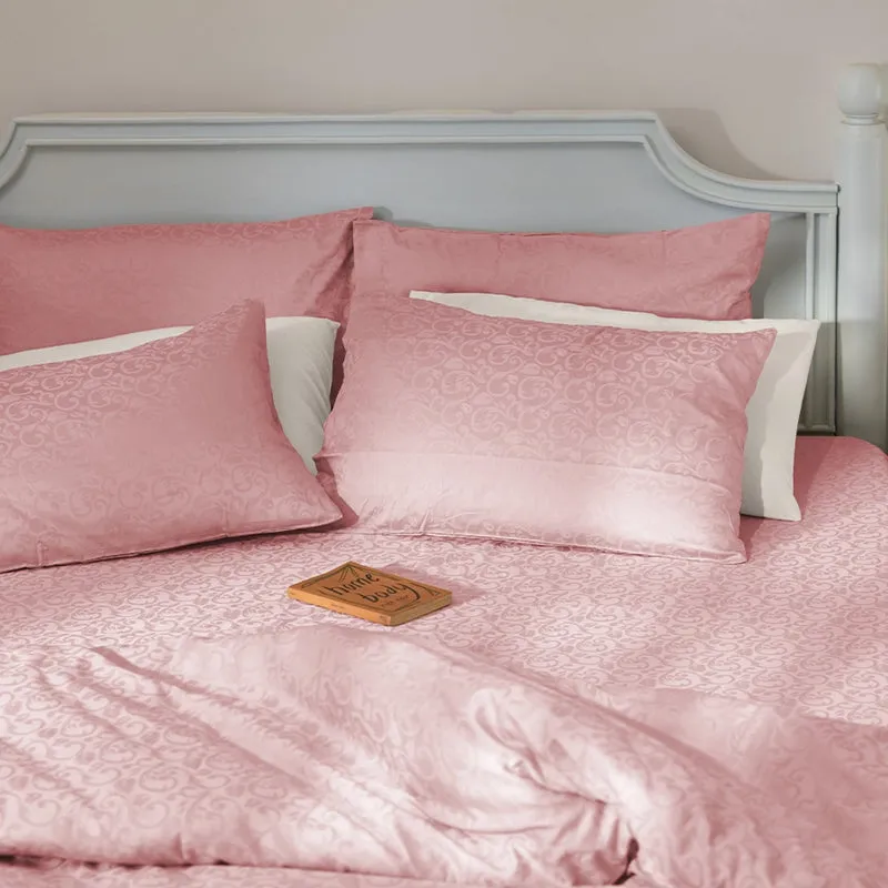 Pink patterned duvet cover styled with pillows and white cushions