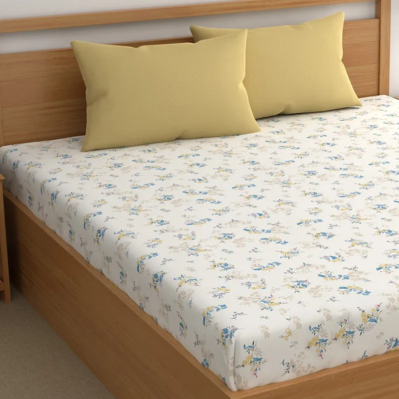 Angled view of white floral bedsheet with yellow pillows