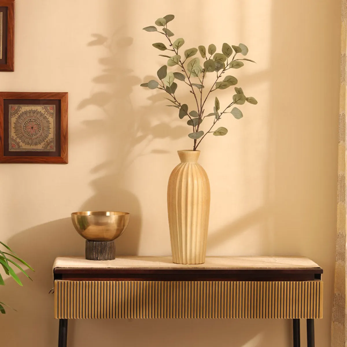 Artificial eucalyptus stem with soft green leaves displayed in a tall vase indoors
