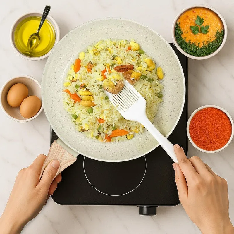 White speckled frying pan with rice on a black cooktop