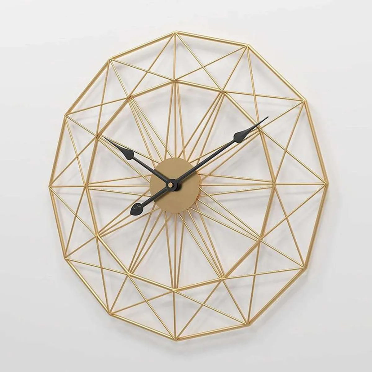 Close view of the round gold geometric wireframe wall clock on a white wall