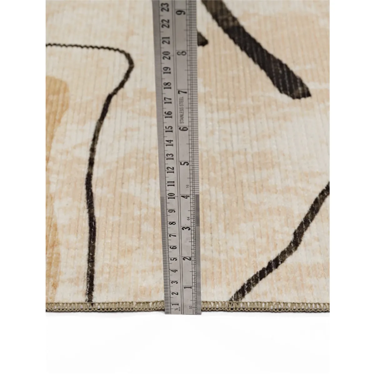 Close-up of the carpet edge and surface texture beside a ruler