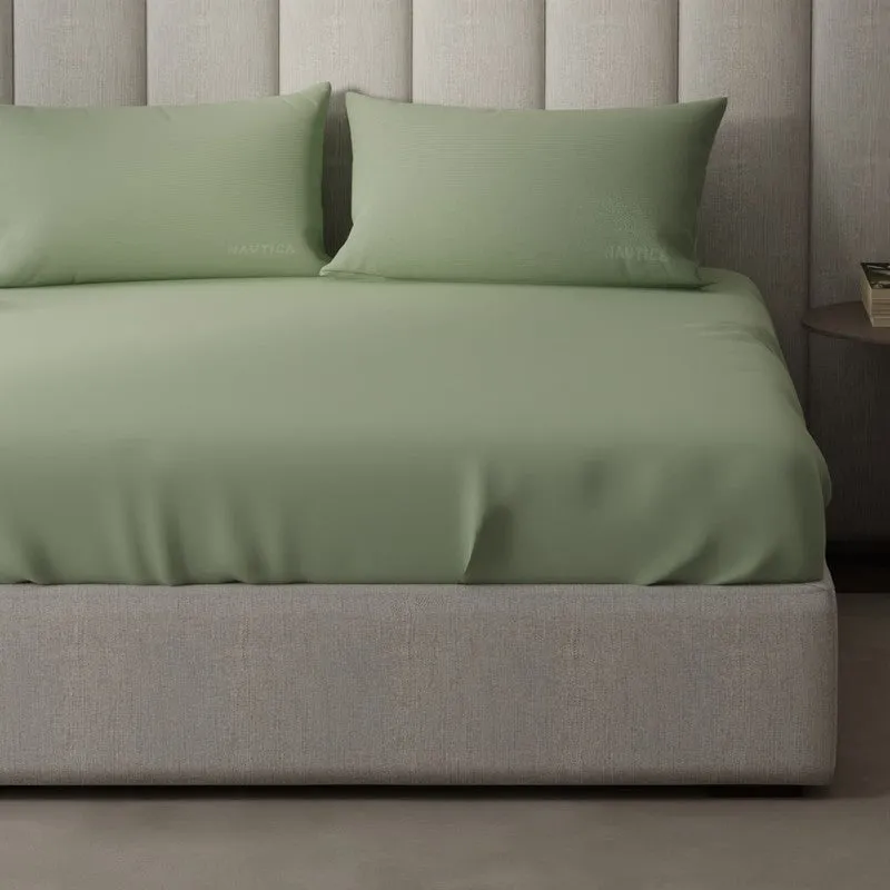 Detail view of olive green bedsheet draped over a modern bed