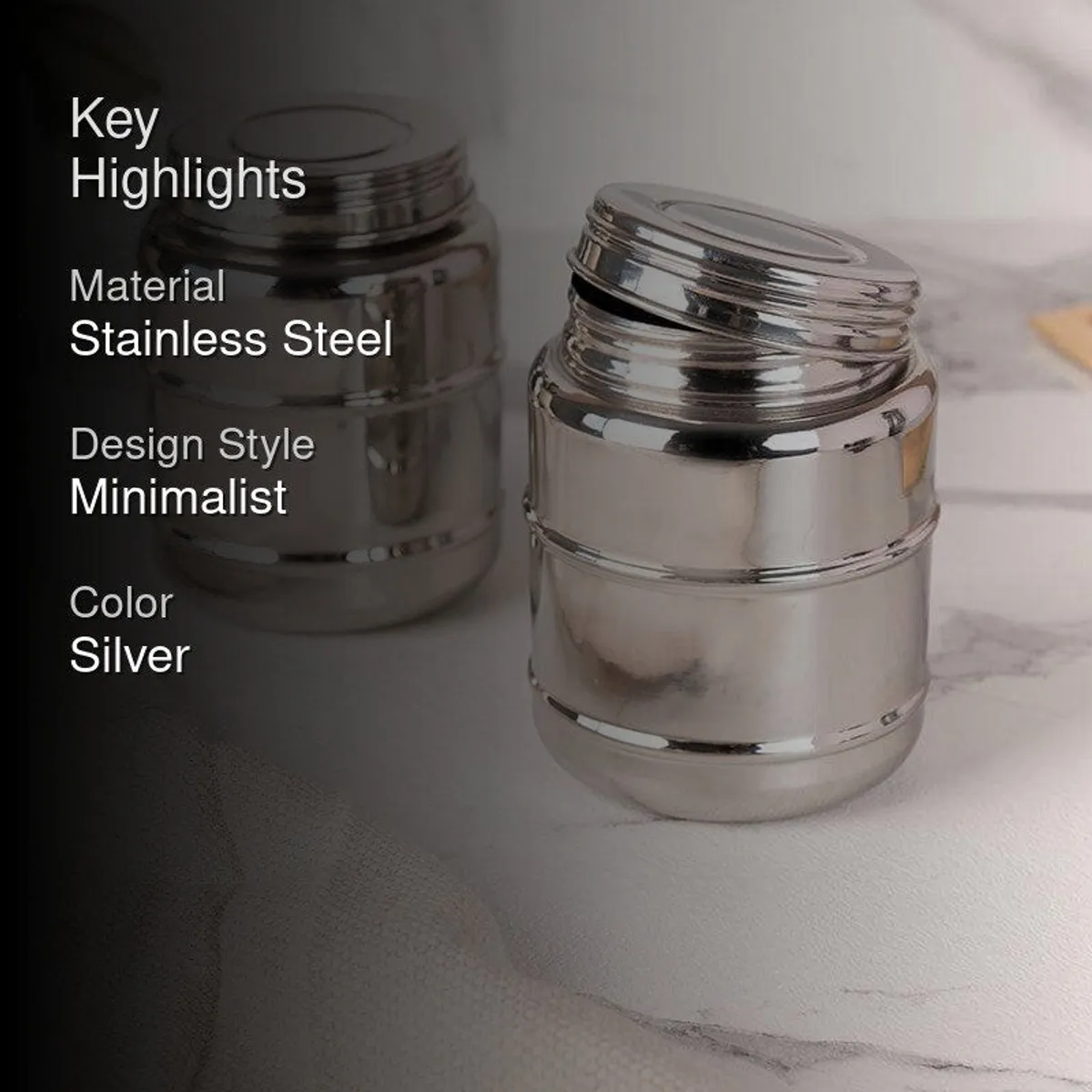 Two glossy silver storage containers arranged on a marble surface
