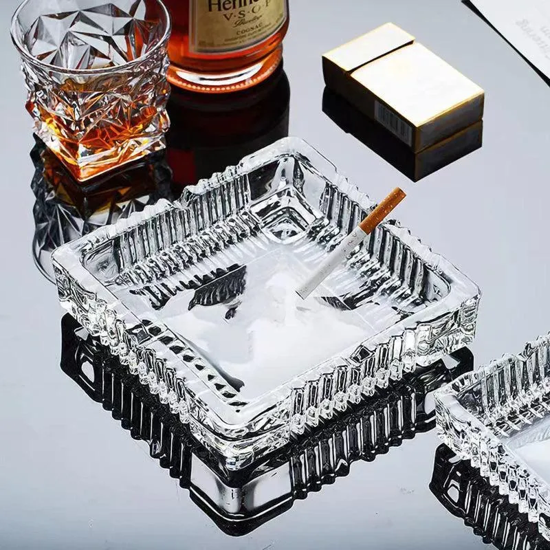 Transparent ribbed glass ashtray styled beside a tumbler and cigar box