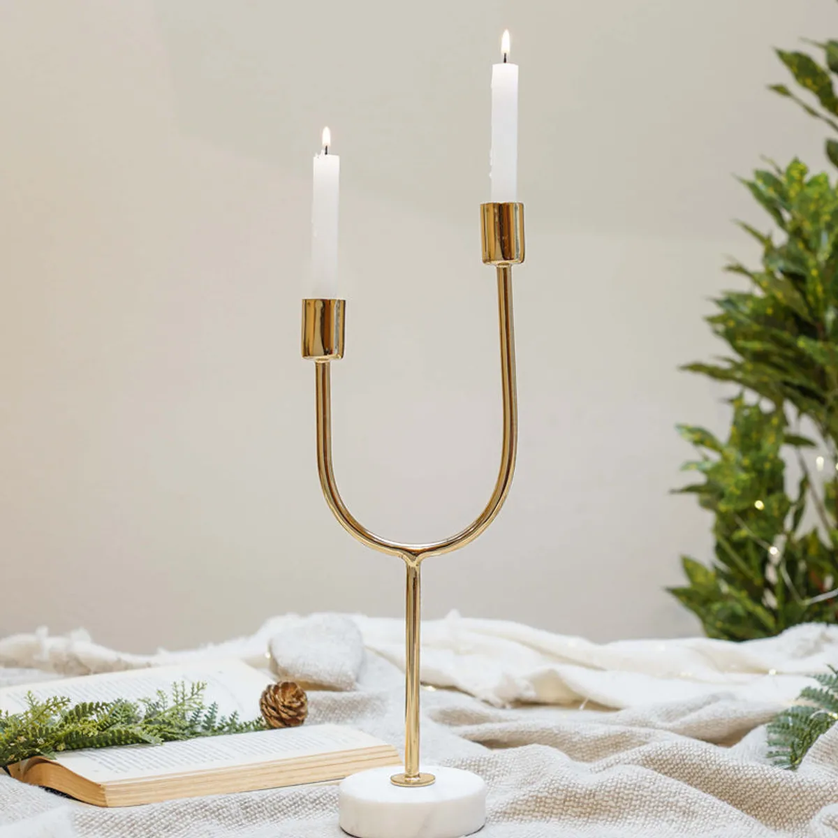 Gold candle holder with white round base styled with books and fabric