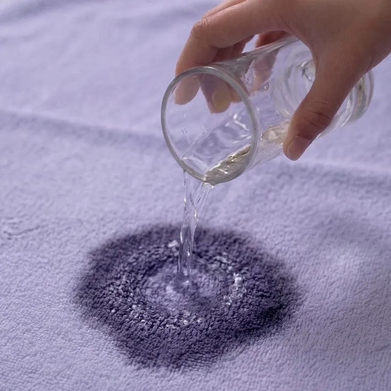 Close-up of water poured onto lavender towel surface