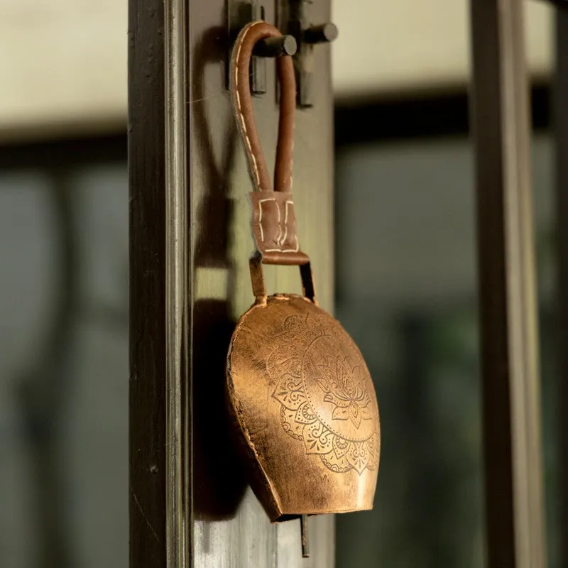 Side view of a copper hanging bell mounted on a dark doorway.