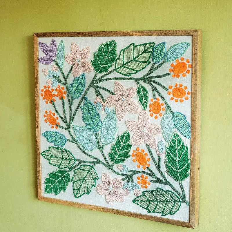 Close angled view of a square wooden-framed floral beaded wall accent