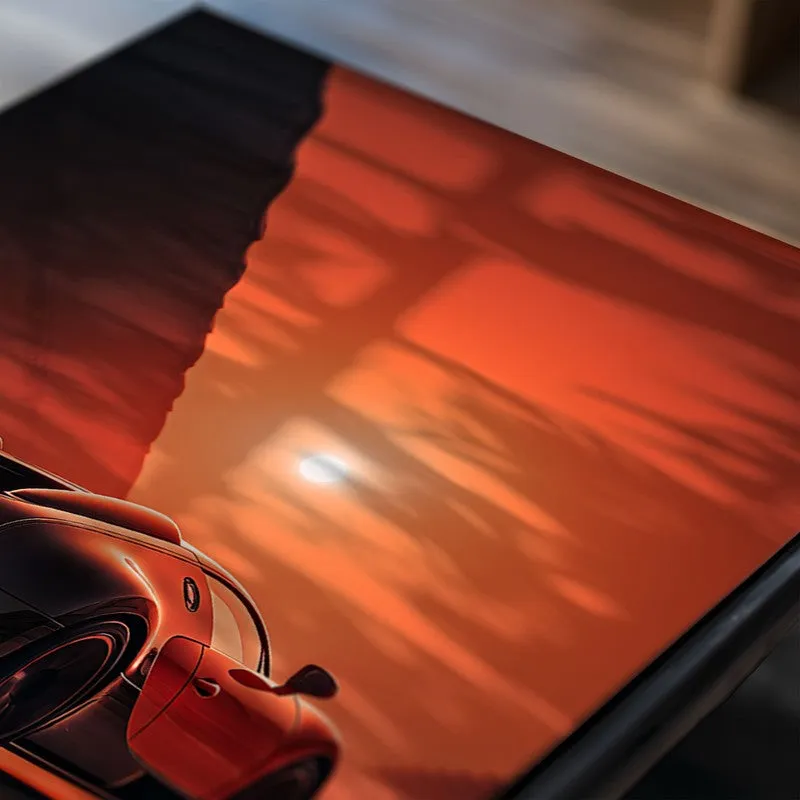 Close-up of a glossy poster with a red sports car against an orange sky
