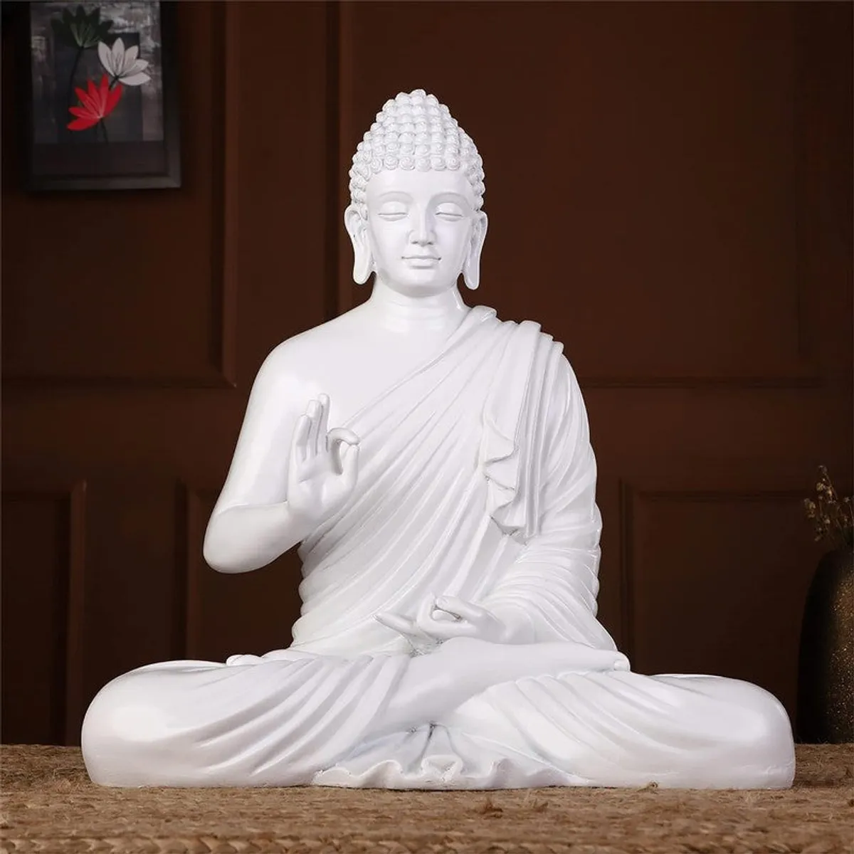 Front view of a white meditating Buddha idol against a dark wooden background