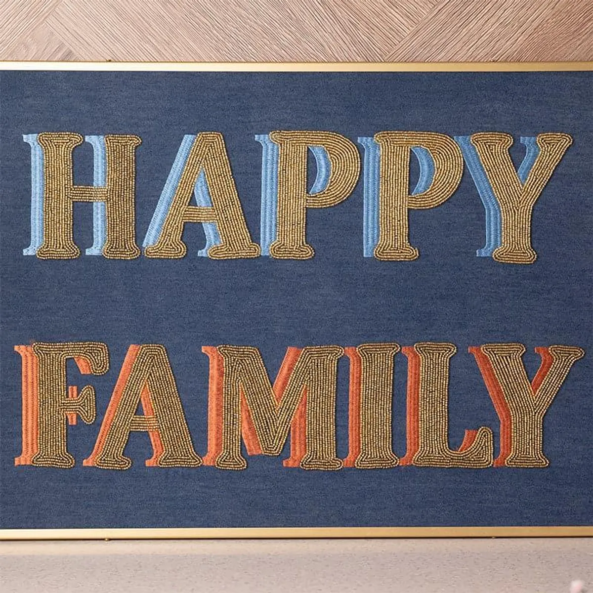 Close-up of colourful beaded HAPPY FAMILY lettering on the blue wall accent.