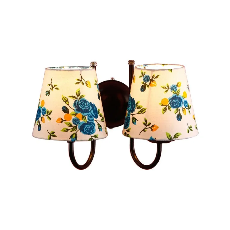 Lit twin wall lamp with blue floral cotton shades on white background
