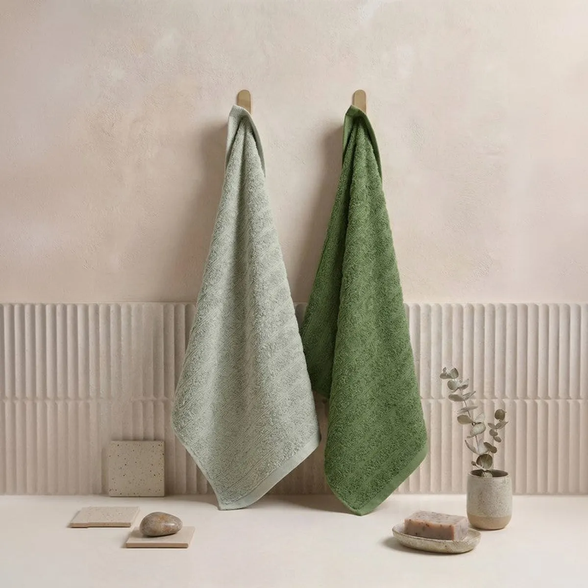 Grey and green towels hanging in a bathroom setting