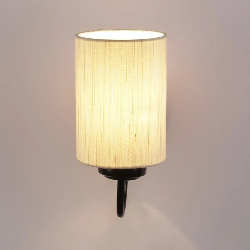 Front view of lit beige cotton wall lamp with cylindrical shade