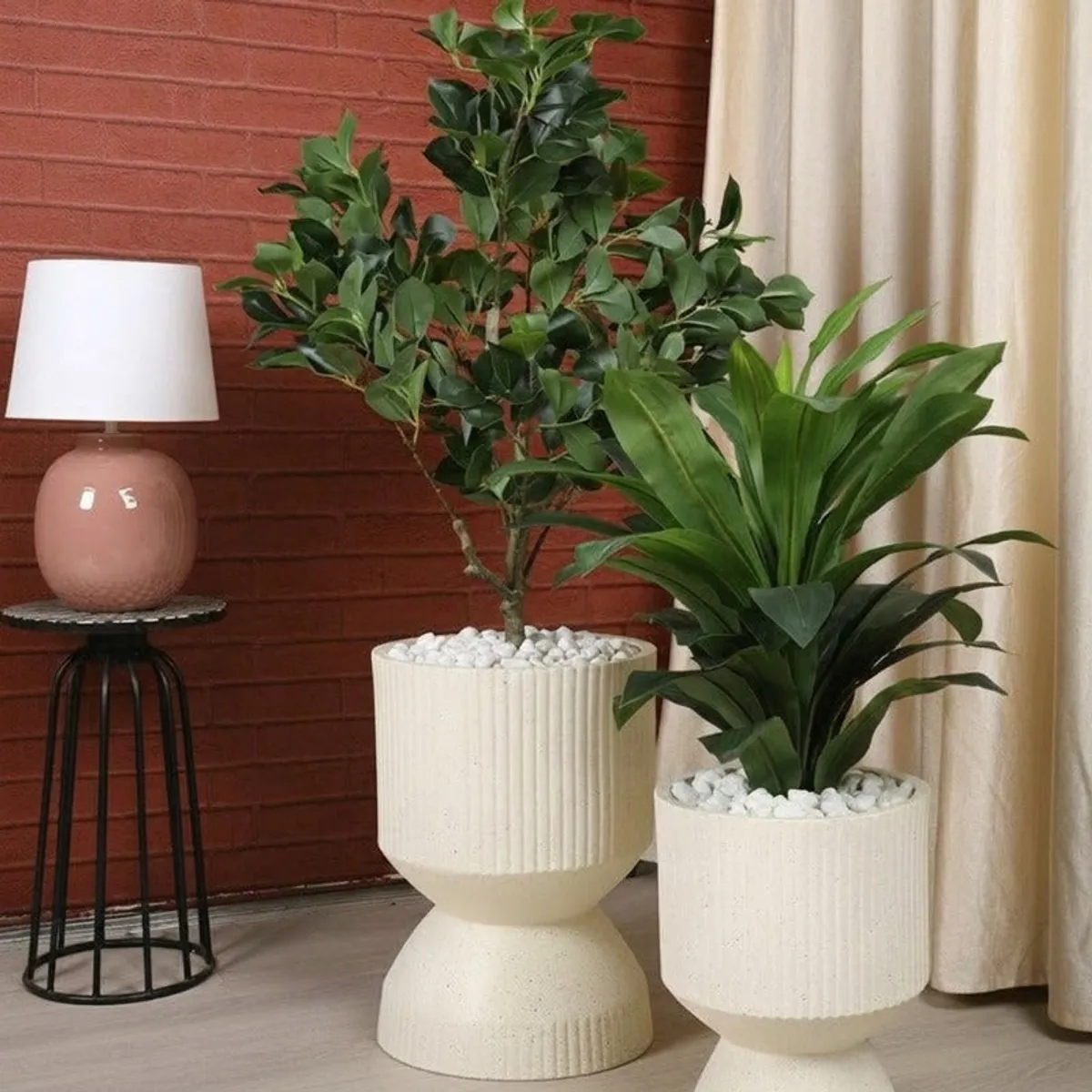 Two off-white ribbed planters displayed with indoor plants in a living space.