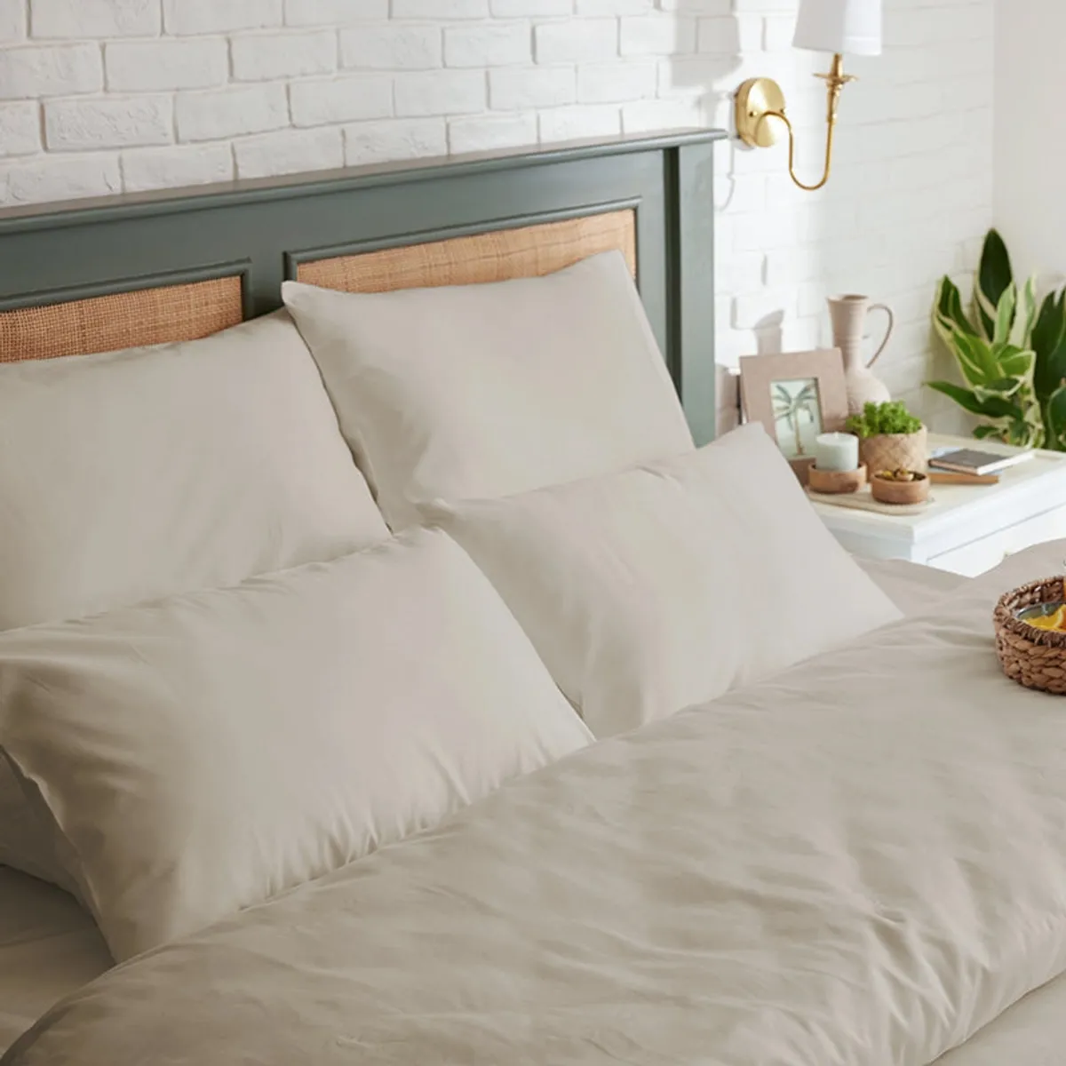 Beige fitted bedsheet and pillows styled in a green and white bedroom