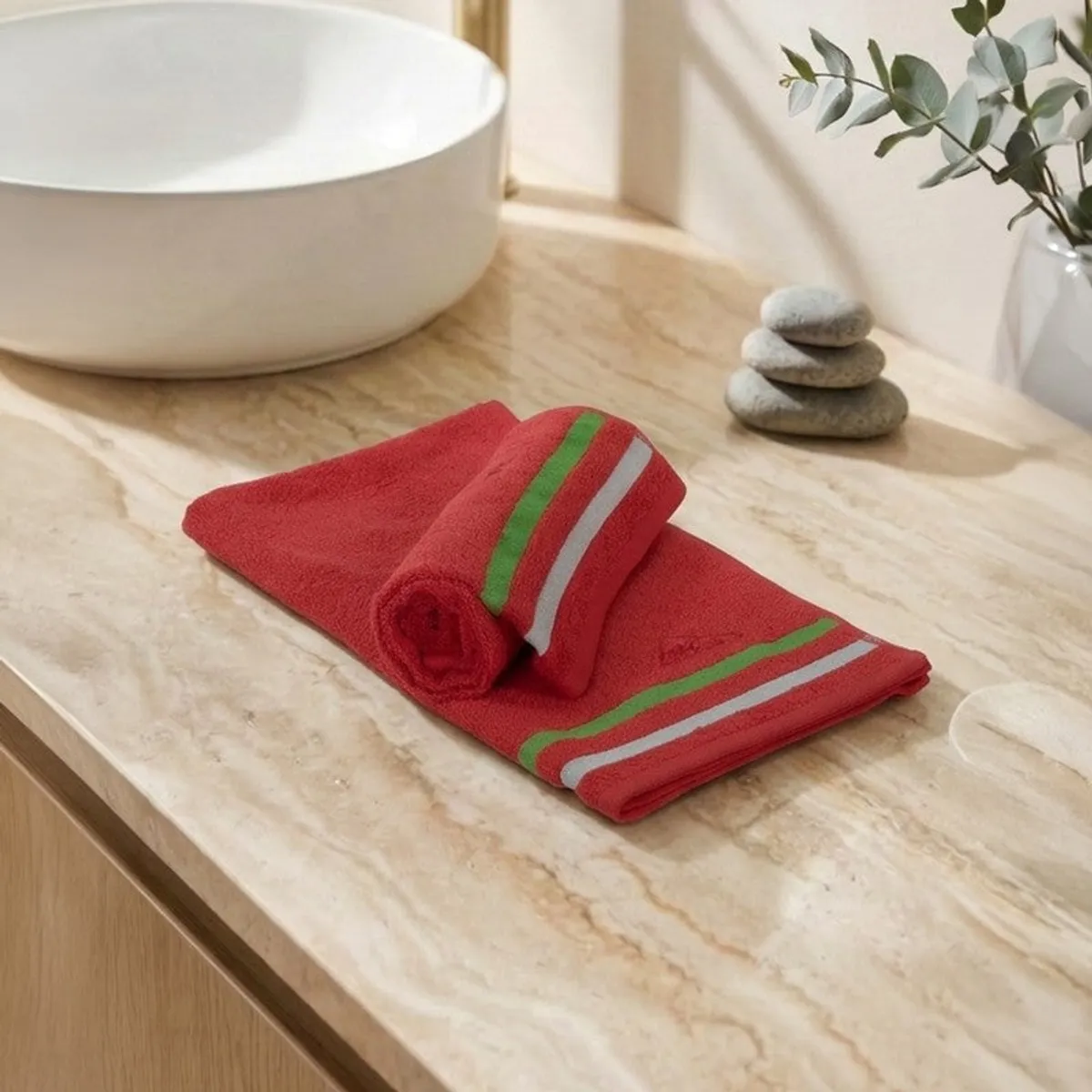 Folded red hand towels with green and white striped borders on a countertop