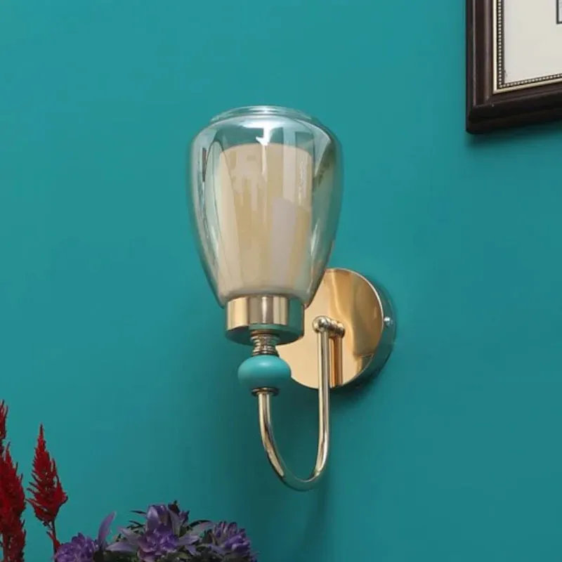 Gold-toned wall lamp mounted on a teal wall in a styled room setting