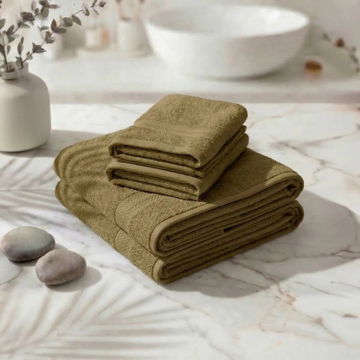 Folded olive green towel set stacked on a marble surface