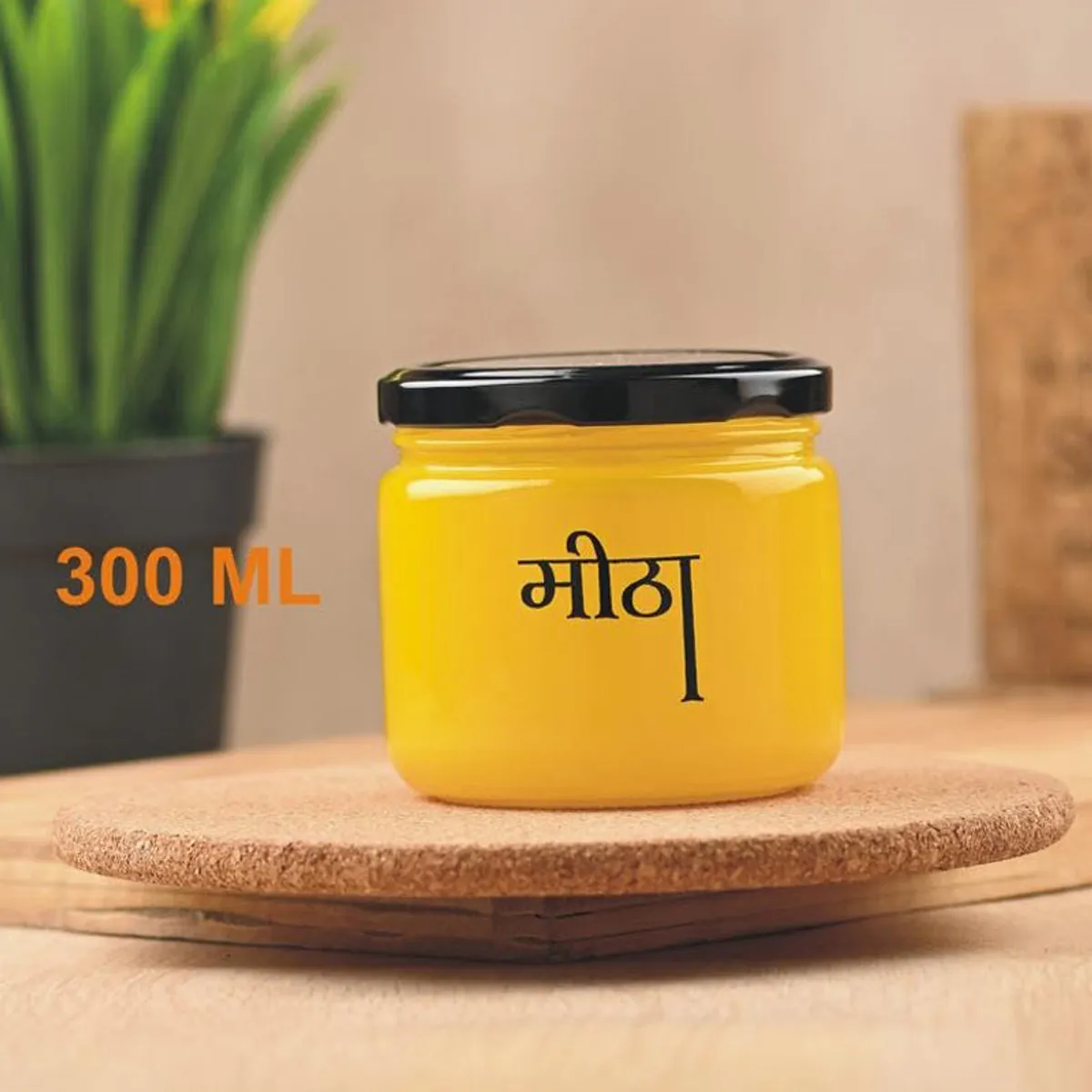Yellow Meetha jar with black lid displayed on a wooden stand