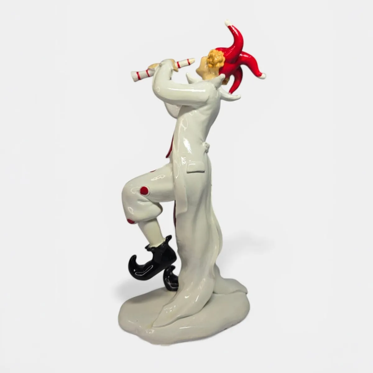 Profile view of clown figurine playing a pipe